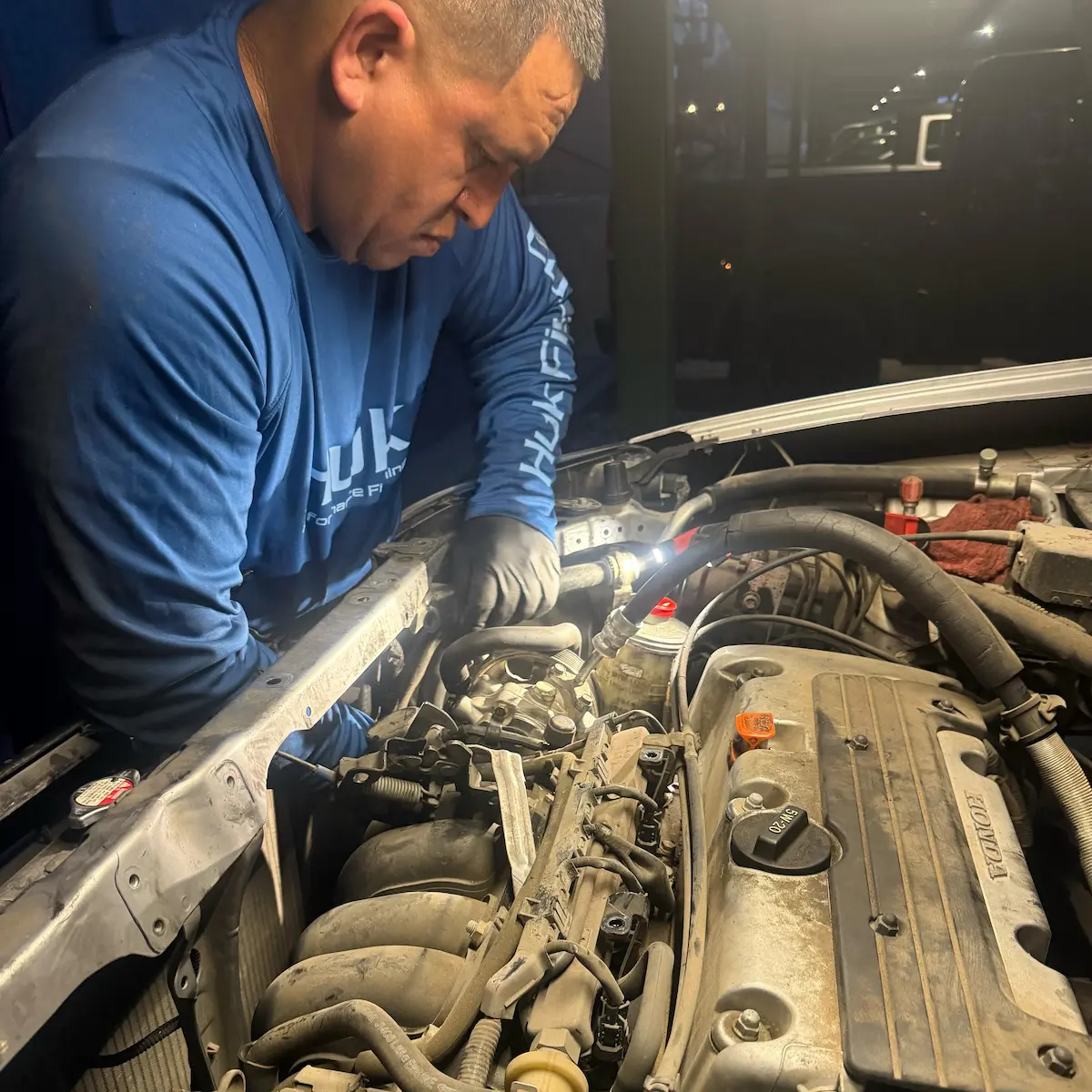Up & Auto technician working under the hood of a Honda in the evening